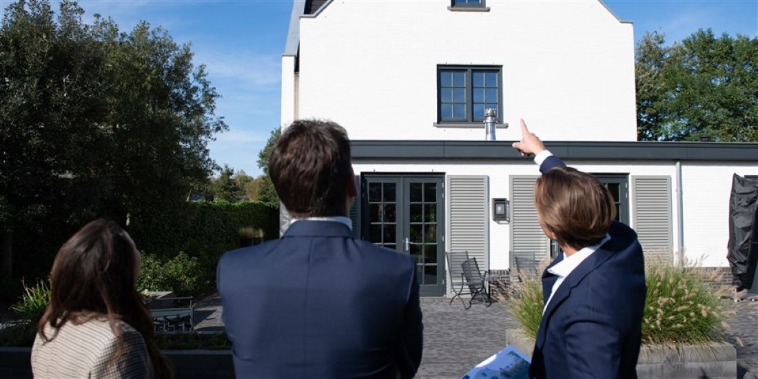 Mensen voor een huis, verwijzend naar stijgende vastgoed- en notarisprijzen in Q2 2025.